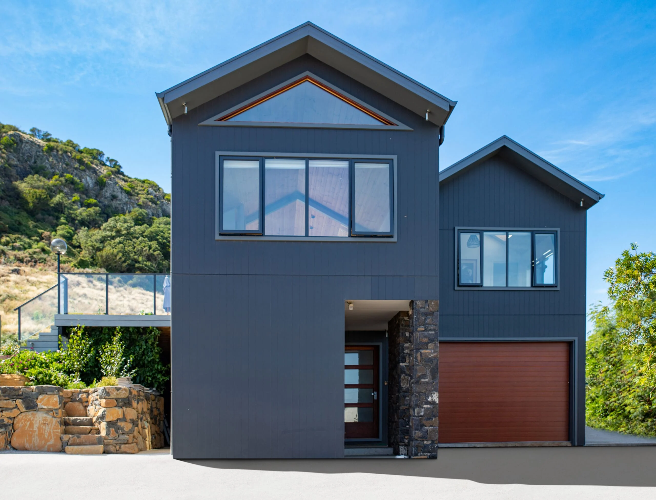 Reference Aerial shot of Driveway Contemporary two-storey home with dark cladding, timber garage door, and stone accents by Coys Constructions.