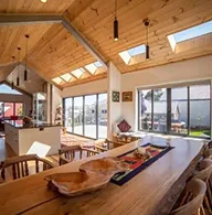Modern open-plan dining and kitchen area with timber ceiling and skylights, designed by Coy’s Constructions in Croydon.