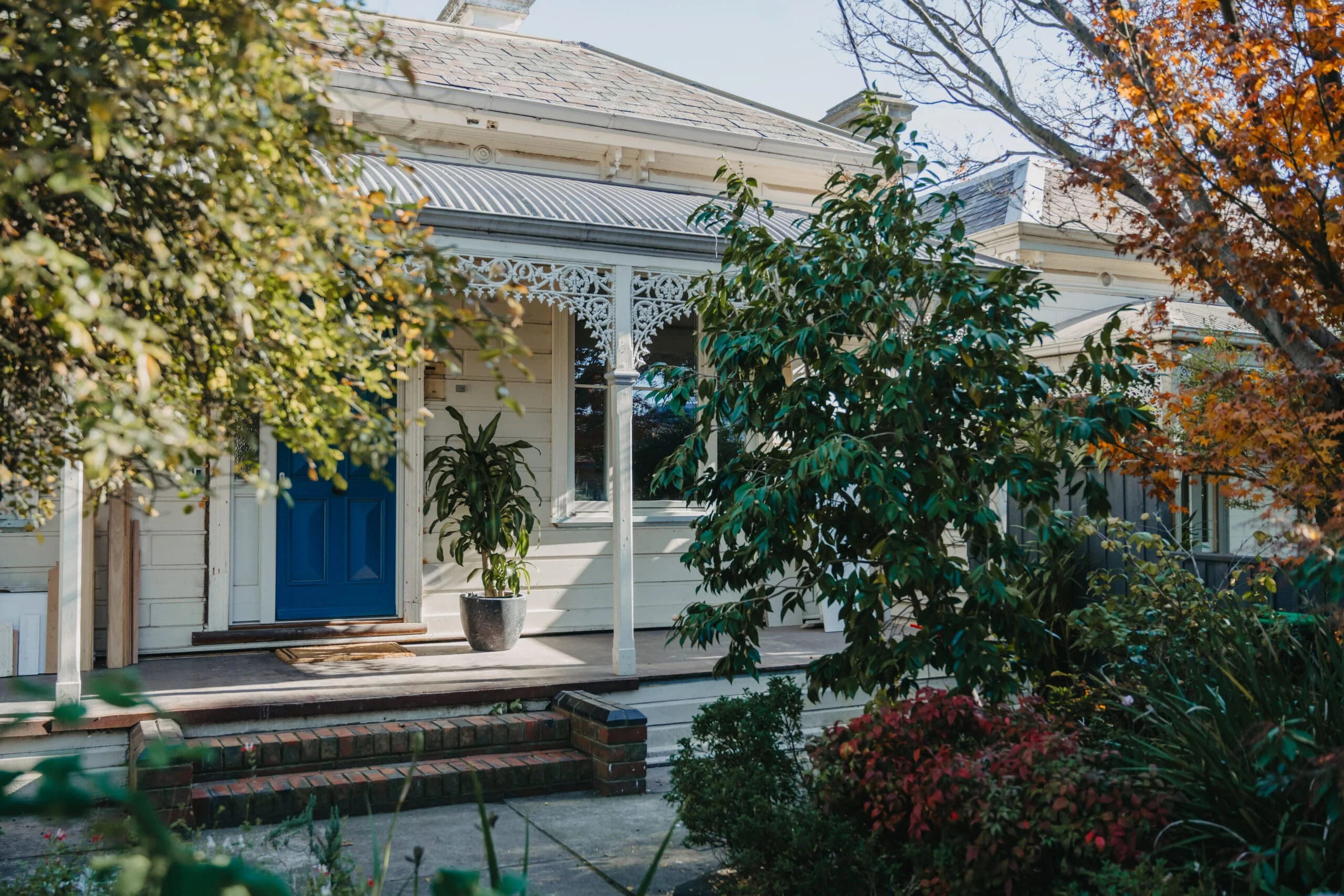MARIAN HAWTHORN Restored heritage home with intricate lacework verandah, classic weatherboard facade, and bold blue front door, beautifully renovated by Coy's Constructions in Australia.